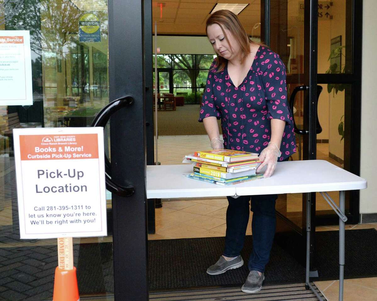 Librarian Ashlee Branning set out books for patron pick-up at the Fort Bend County Library, Cinco Ranch Branch, Katy, TX on Friday, March 20, 2020. Library officials recently announced curbside pick-up services were being canceled for at least weeks.