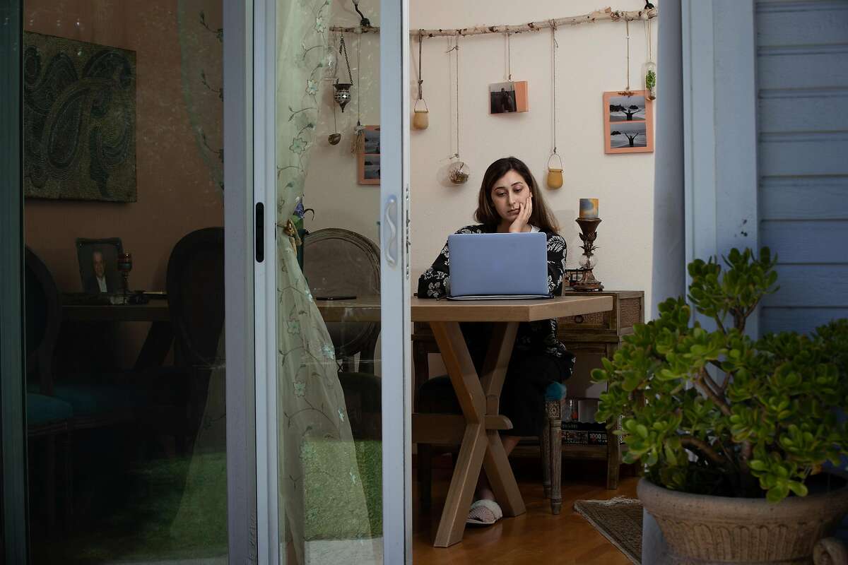 Delaram Mehrkish, 25, of San Jose, does work on her computer for the Red Cross at home Friday, March 20, 2020, in San Jose, Calif. Her other job at a daycare has been shut down.
