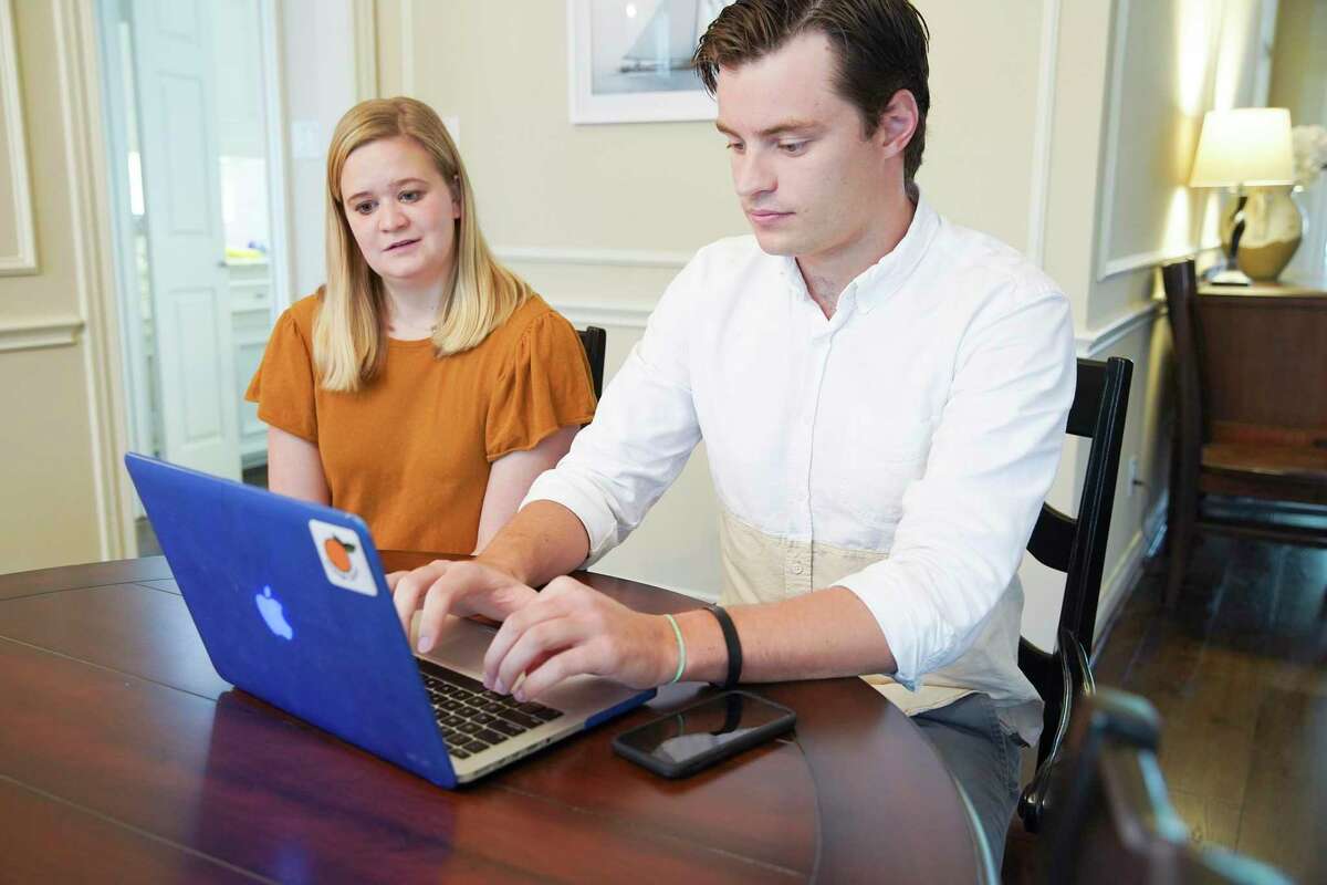 Baylor medical school student Andrew Jensen checks his laptop with his fiancé Annie Crea in his parent's Sugarland, Texas home on Friday, March 20, 2020.