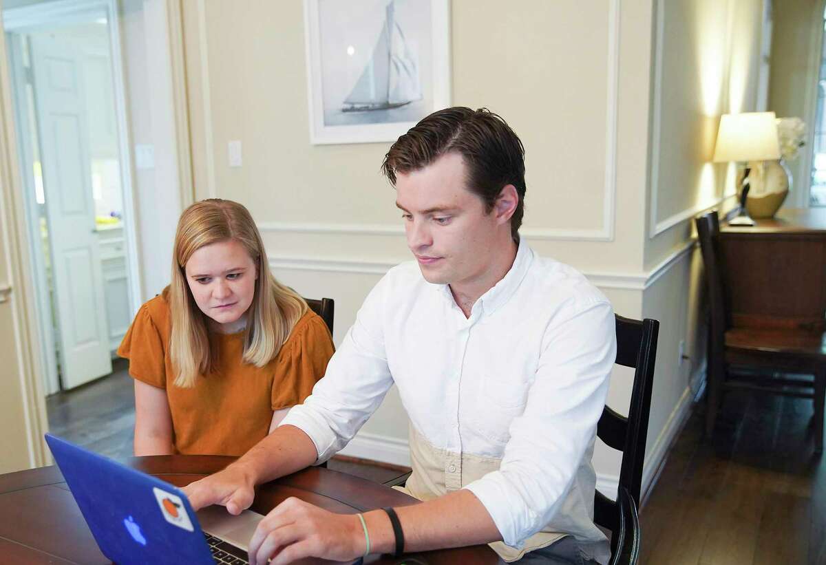 Baylor medical school student Andrew Jensen checks his laptop with his fiancé Annie Crea in his parent's Sugarland, Texas home on Friday, March 20, 2020.