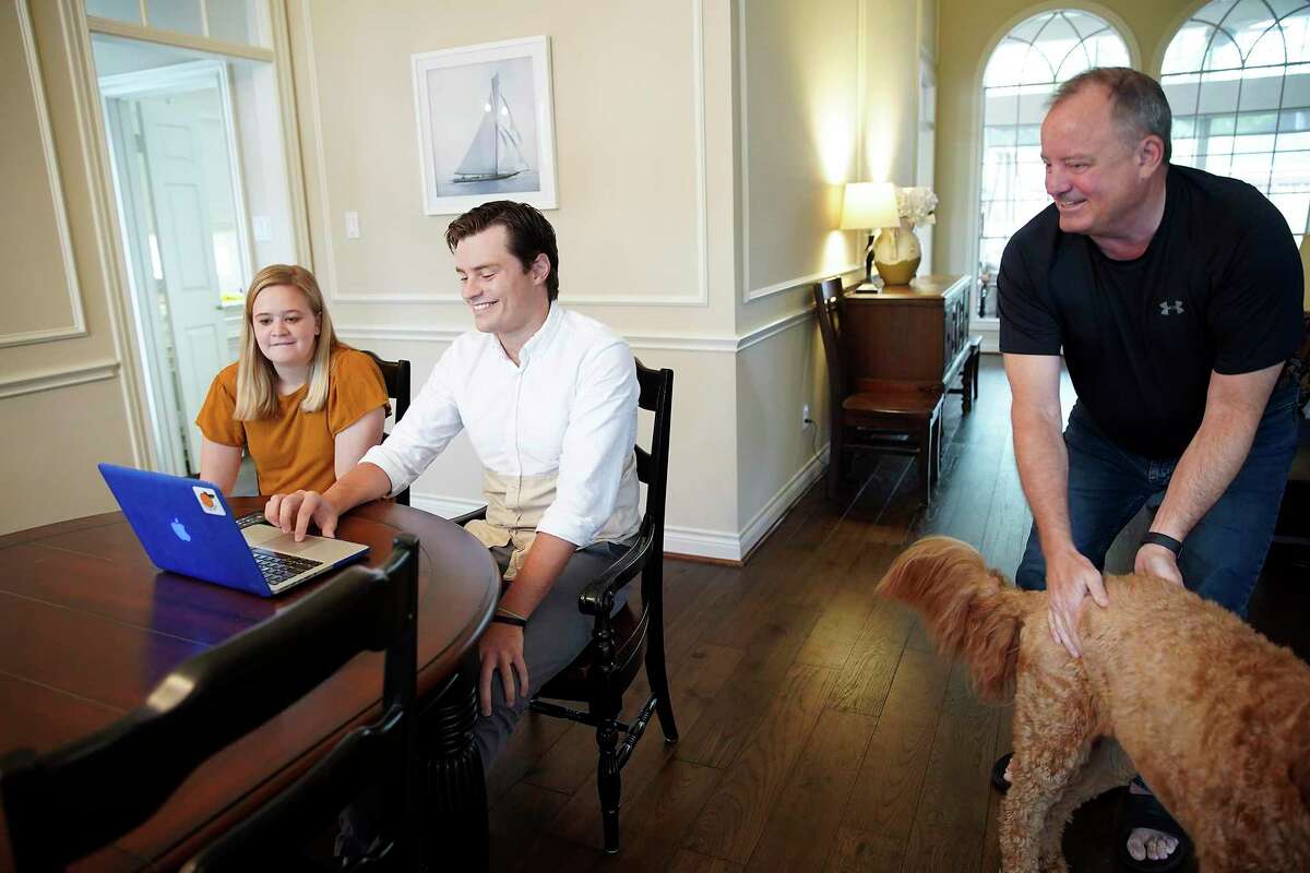 Baylor medical school student Andrew Jensen checks his laptop with his fiancé Annie Crea and dad, Leif, in his parent's Sugarland, Texas home on Friday, March 20, 2020.
