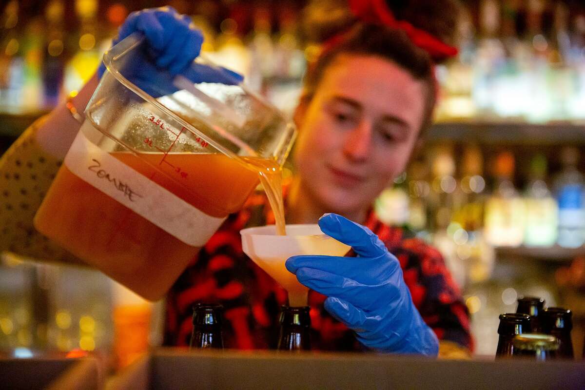 Jeanie Grant, bar manager of Palmetto, pours pre-mixed drinks into bottles at the Kon-Tiki Bar in Oakland, Calif. on Friday, March 20, 2020. Starting Friday evening the Kon-Tiki Bar with be offering deliveries to Oakland residents of mixed drinks bottled at the restaurant, including the House Zombie, The Ko-Tiki Grog, Virgin's Sacrifice, Man Tai and a 22 oz. Ma Kua for two. The ABC has relaxed regulations for bars and restaurants during shelter in place, allowing them to now offer cocktail deliveries and drive-through options for alcohol.