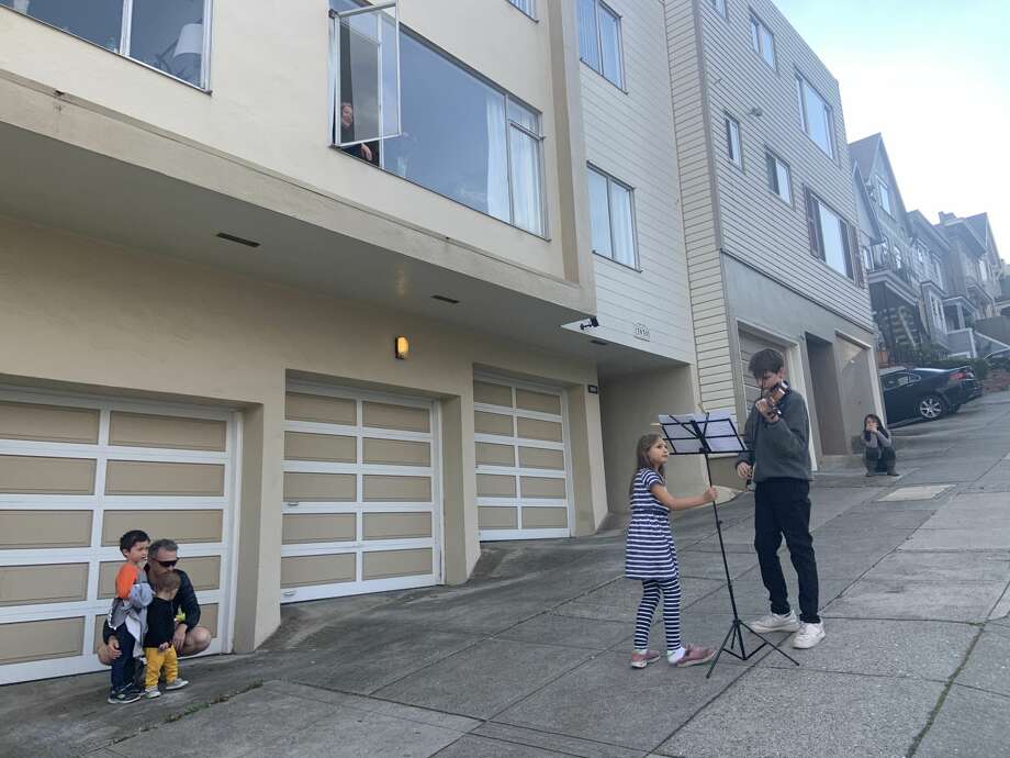 Restant bien à plus de six pieds des autres, un garçon joue de son violon pour les voisins de San Francisco au milieu d'un refuge pour lutter contre la propagation de COVID-19 le vendredi 20 mars 2020. Photo: A. Graff
