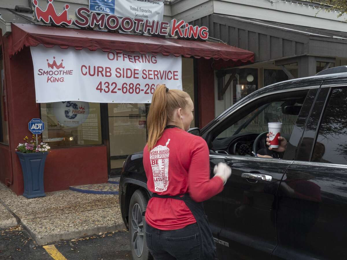 Kymberly Bedingfield delivers a smoothie to Scott Church 03/21/2020 outside Smoothie King after the store has implemented online or call-in ordering and curbside delivery. Tim Fischer/Reporter-Telegram