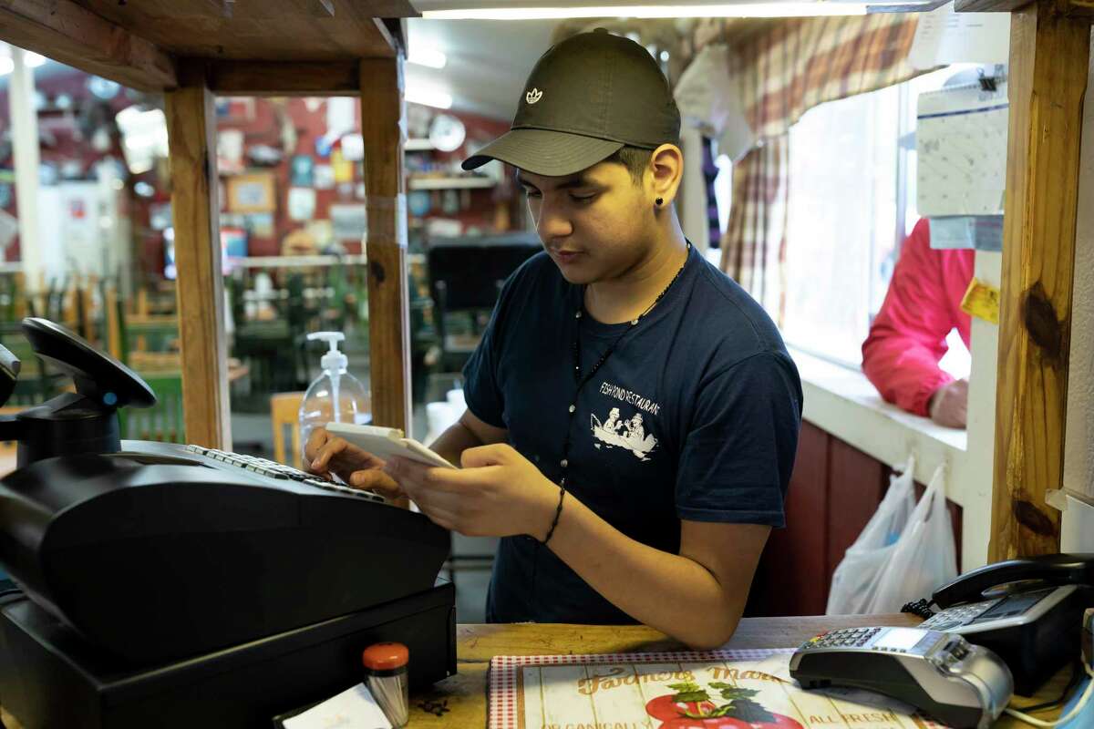 Jose Rodriguez rings up a check for a pickup delivery at Fish Pond Restaurant, Saturday, March 21, 2020. The restaurant has taken extra precautions against the spread of COVID-19 to ensure the safety of their employees and customers.