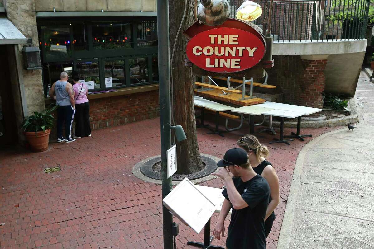 People order take-out food at The County Line restaurant on the River Walk on Thursday, March 19, 2020. The City of San Antonio ordered non-businesses closed to curb the spread of the coronavirus. Restaurants had to close their dining areas though they can fill orders for take-out, drive-thru and delivery.