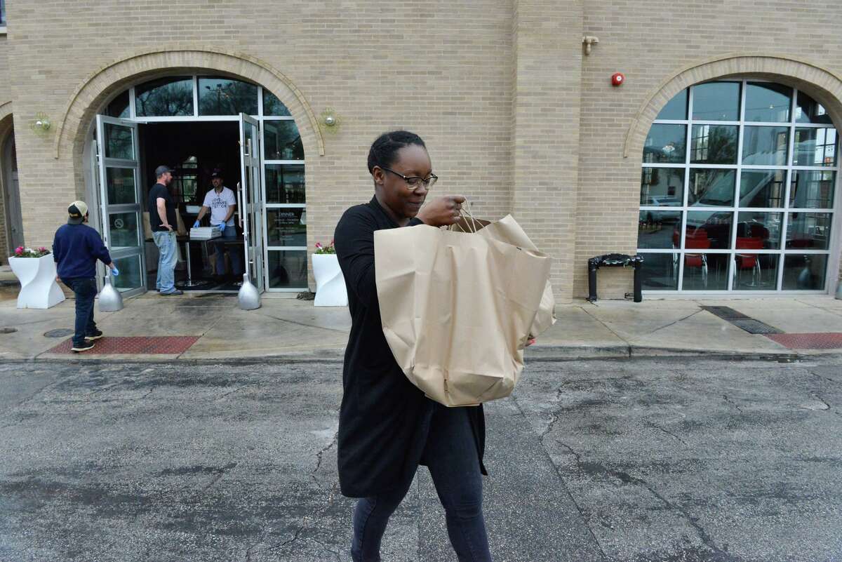 Ajisha Sutton who was laid off from the Holiday Inn Riverwalk looks over her bags of food during an outreach to service industry workers laid off during coronavirus stay-at-home orders.