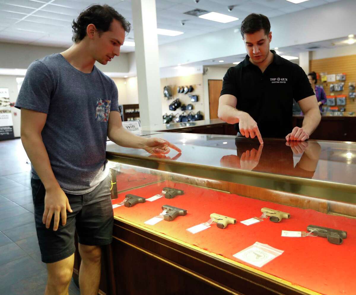 Aaron Andrus shops for a gun with the help of Louie Uribe, a sales associate at Top Gun Range, in Houston,Thursday, March 19, 2020. Gun sales have risen as people react to the uncertainty of the coronavirus pandemic.