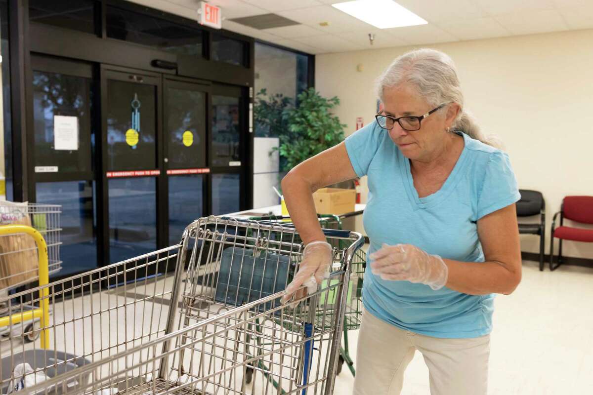 15 year volunteer Paula Stoebner wipes down shopping carts with disinfectant wipes after in Tomball, Friday, March 20, 2020. The food pantry has taken extra precautions in compliance with the Center of Disease Control and Preventions recommendations to stop the spread of COVID-19.