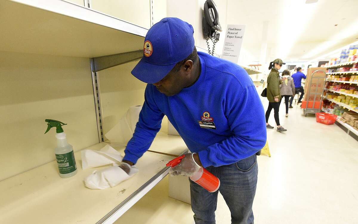 An employee cleans displays as they prepare to re-stock paper products while customers shop at the Stanford Shop Rite on March 14, 2020.