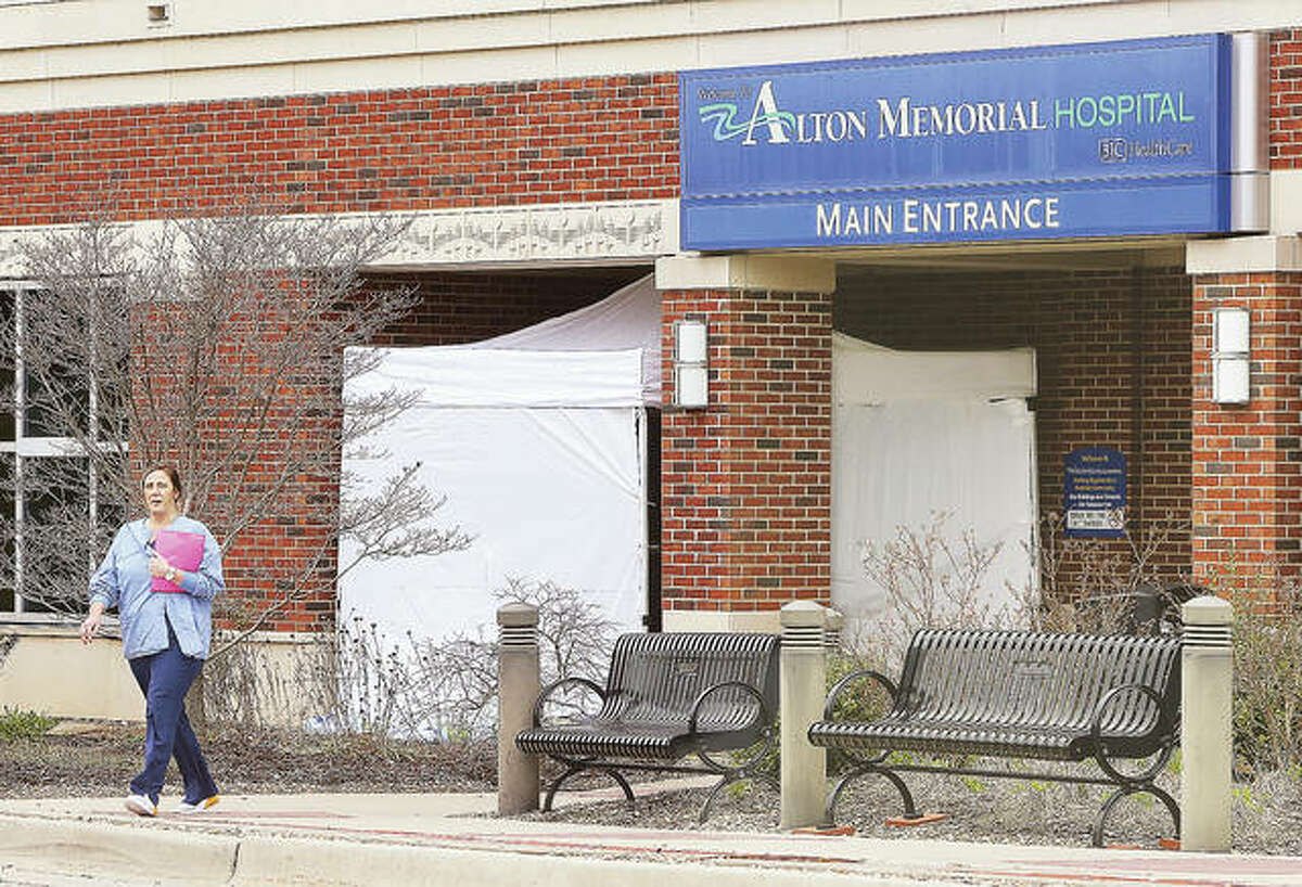 A woman walks out of the main public entrance to Alton Memorial Hospital Monday where a tent-like structure has been erected. Structures have been put up at the Emergency entrance to the hospital as well, apparently to screen visitors for signs of the COVID-19 virus. OSF St. Anthony’s Hospital in Alton put visitation restrictions into place Monday and Alton Memorial Hospital plans to do the same starting Tuesday.