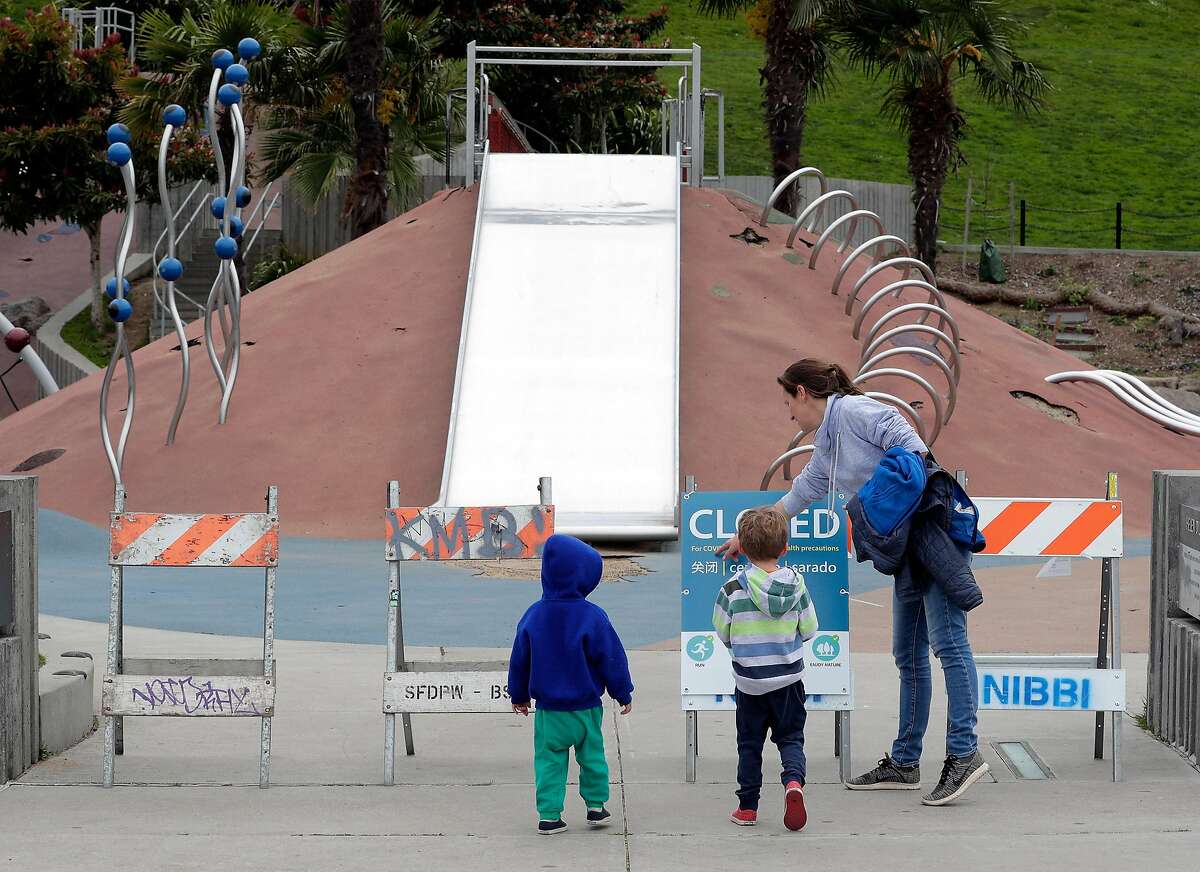 A local mom and her two boys stop at the closed Helen Diller Playground in Dolores Park following Mayor London Breed’s decision to have city parks close children’s playgrounds to prevent the spread of the coronavirus in San Francisco, Calif., on Monday, March 23, 2020.