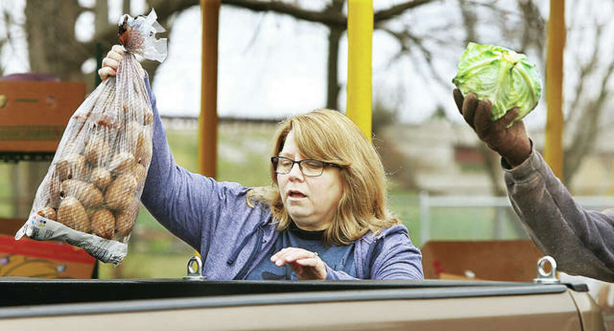 Volunteers at the Hope Community Center in Cottage Hills load food into the vehicles of the needy Tuesday from a drive-through operation in the parking lot. Normally people enter the center for food, but concerns of spreading the COVID-19 virus has forced pantries to adapt.