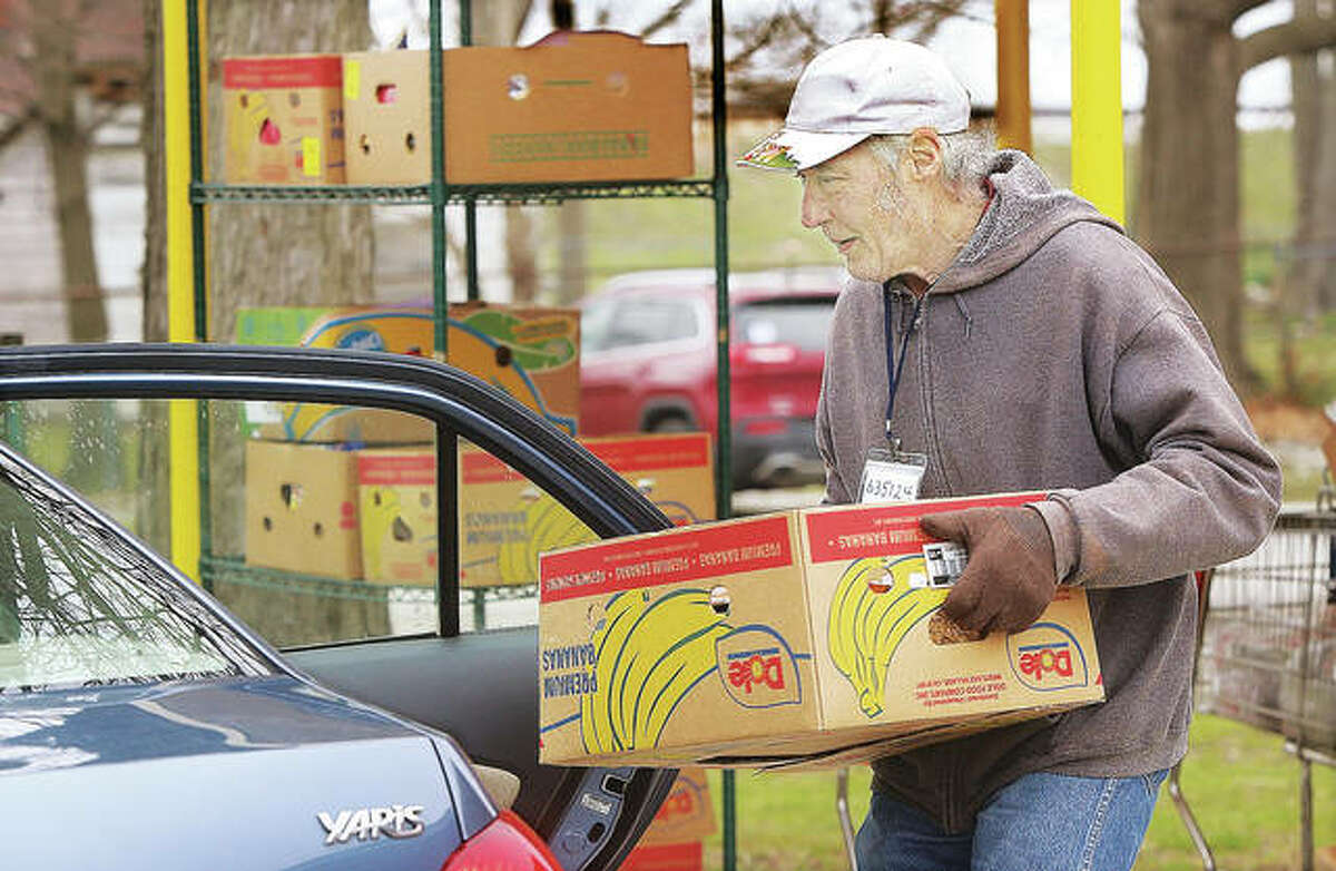 A volunteer at the Hope Community Center in Cottage Hills loads a box of food into a woman’s car during a drive-through operation on Tuesday.