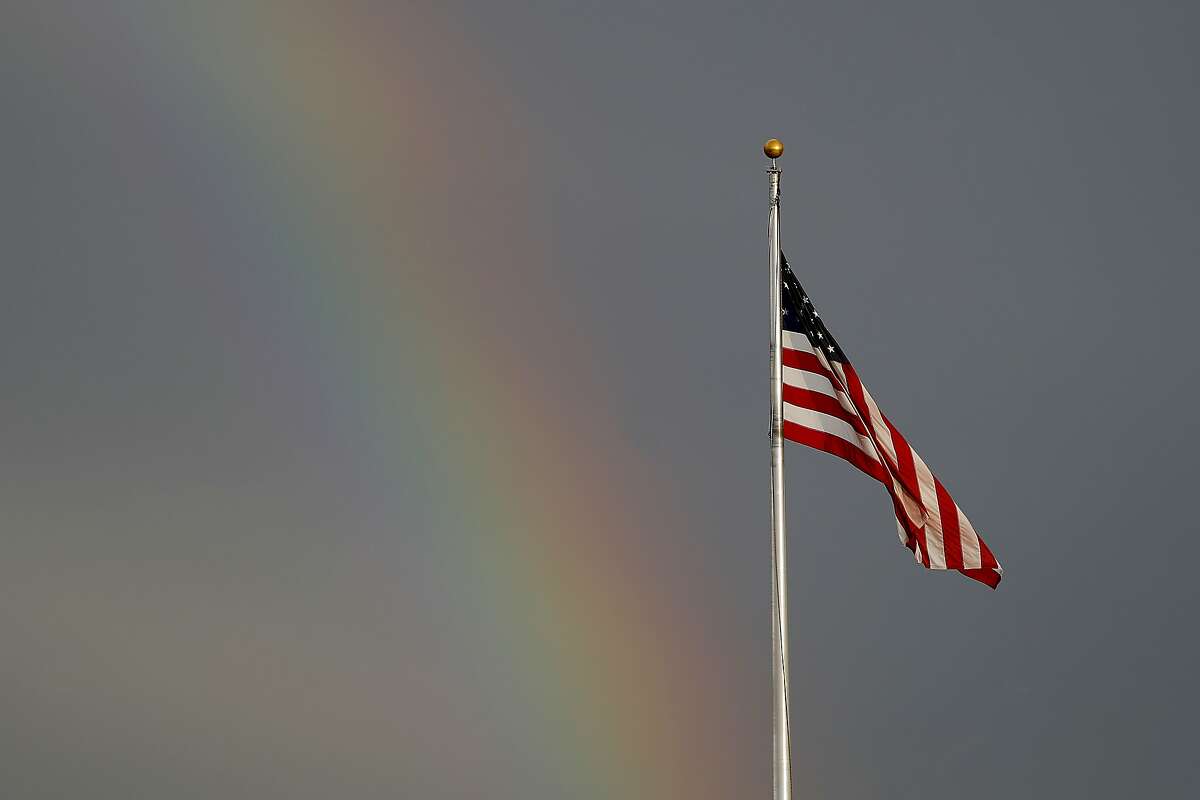 A rainbow is visible next to a United States flag along Route 49, Friday, March 20, 2020, in Hattiesburg, Miss. In a matter of days, millions of Americans have seen their lives upended by measures to curb the spread of the new coronavirus. For most people, the new coronavirus causes only mild or moderate symptoms. For some it can cause more severe illness. (AP Photo/Julio Cortez)