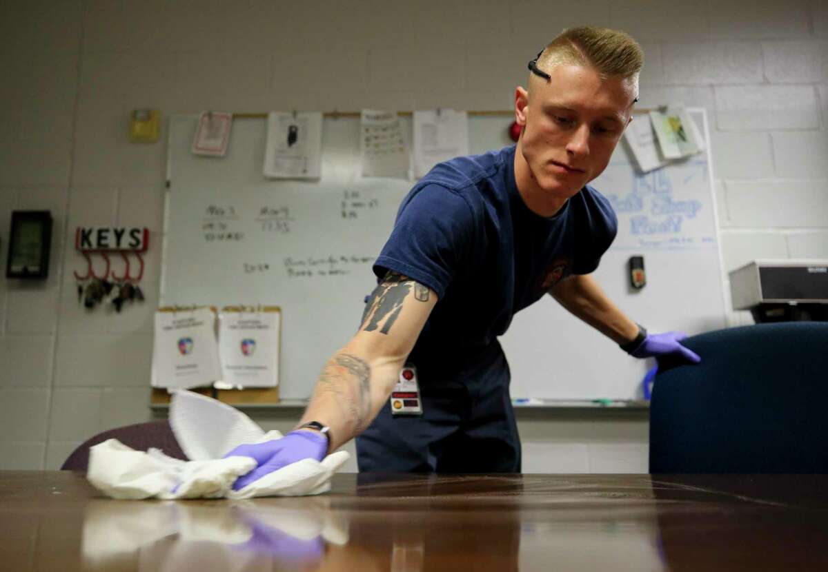 Firefighter Braxton Cole disinfects the dining room table inside the Stafford Fire Department Station 1 on Tuesday, March 24, 2020, in Stafford, Texas.