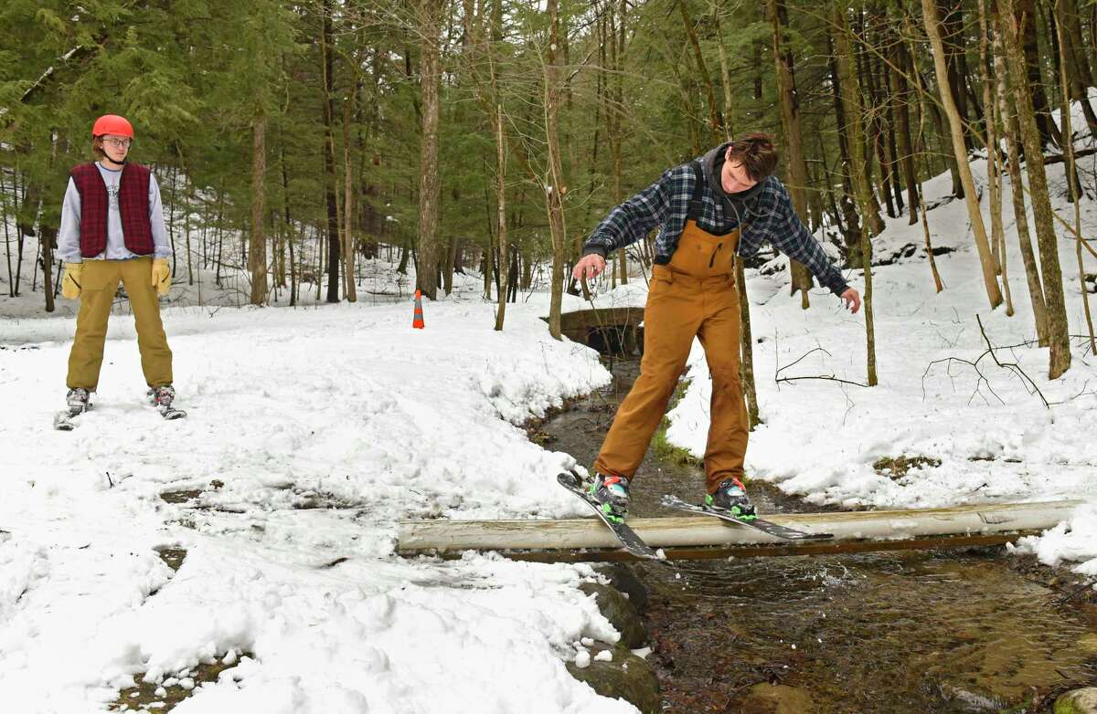 Henry Tucker, 18, of Saratoga Springs, left, watches as his friend Cam Sgambati, 19, ski down a hill in the woods and grind on a pipe they placed over a stream in Saratoga Spa State Park on Tuesday, March 24, 2020 in Saratoga Springs, N.Y (Lori Van Buren/Times Union)
