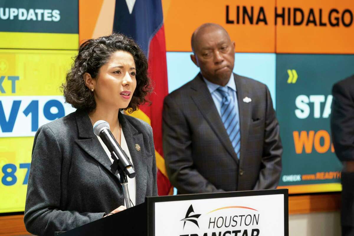 Harris County Judge Lina Hidalgo speaks as Houston Mayor Sylvester Turner listens during a press conference announcing that the county will adopt a "Stay Home, Work Safe" strategy until April 3, Tuesday, March 24, 2020, at TranStar in Houston.