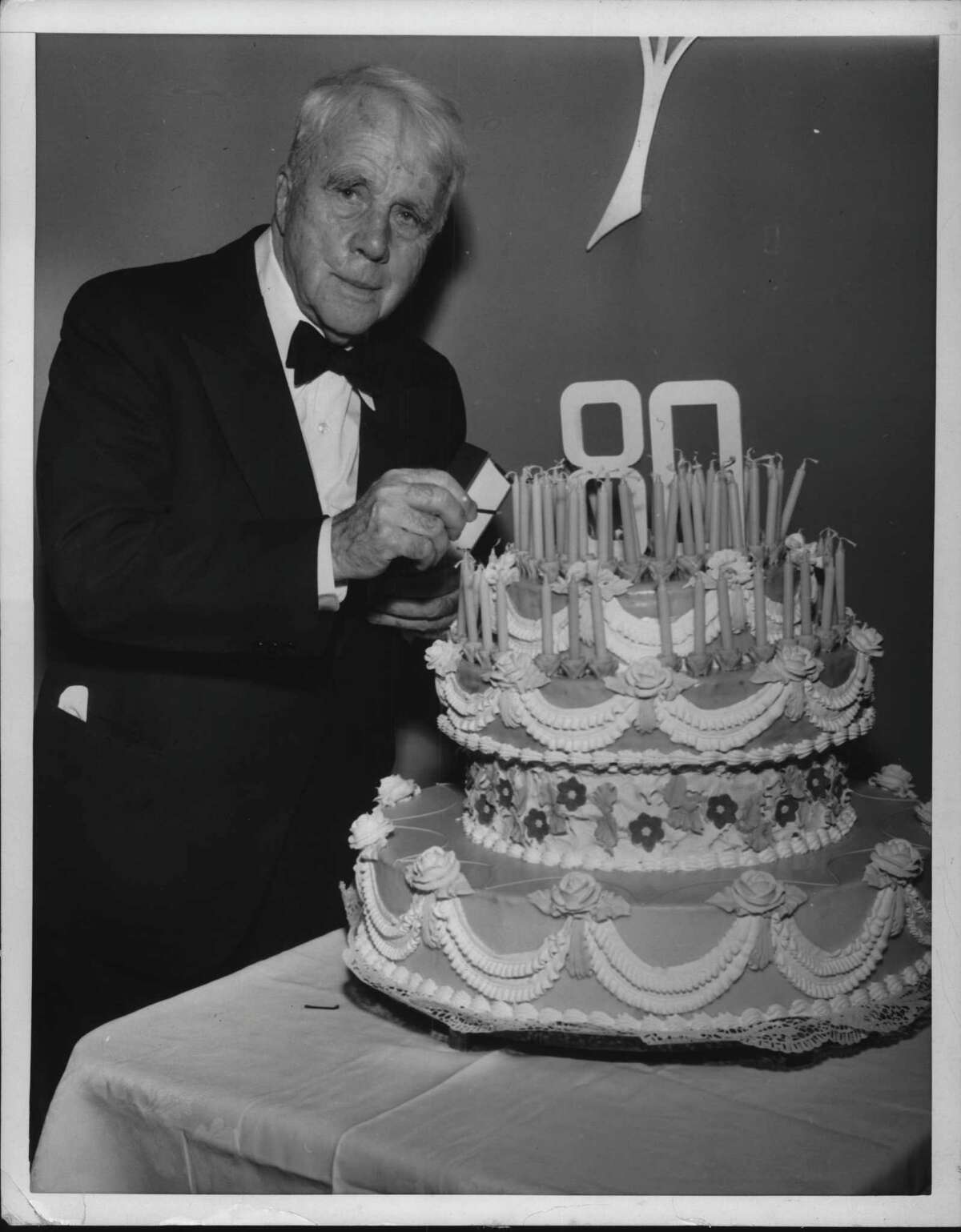 New York - Robert Frost, four time Pulitzer Prize winner and one of America's most noted living poets, prepares to light the candles on his birthday cake at a party given him by Edgar T. Rigg, President of Henry Holt & Co., the poet's publisher. The 80th birthday celebration at the Waldorf-Astoria was attended by some 80 American leaders in the fields of literature, the arts, government and business. March 25, 1954 (Times Union Archive)