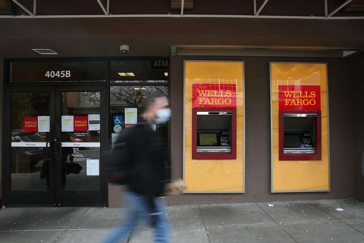 A pedestrian wearing a mask walks past a temporarily closed Wells Fargo branch due to the coronavirus shelter in place on 24th Street on Tuesday, March 24, 2020 in San Francisco, Calif.