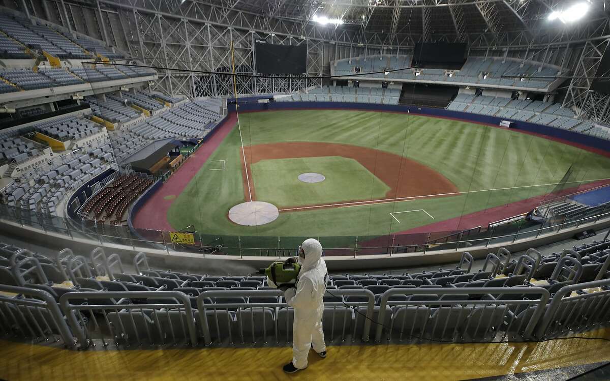 A worker wearing protective gears disinfects as a precaution against the new coronavirus at Gocheok Sky Dome in Seoul, South Korea, Tuesday, March 17, 2020. The Korea Baseball Organization has postponed the start of new season to prevent the spread of the new coronavirus. For most people, the new coronavirus causes only mild or moderate symptoms. For some it can cause more severe illness. (AP Photo/Lee Jin-man)