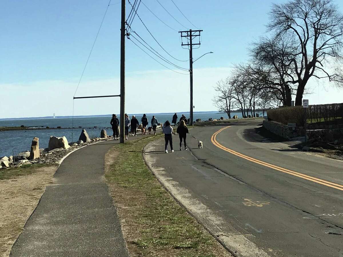 People walking alongside the Compo Beach area late Tuesday afternoon. The beach was not crowded despite the good weather. Taken March 24, 2020 in Westport, Conn.