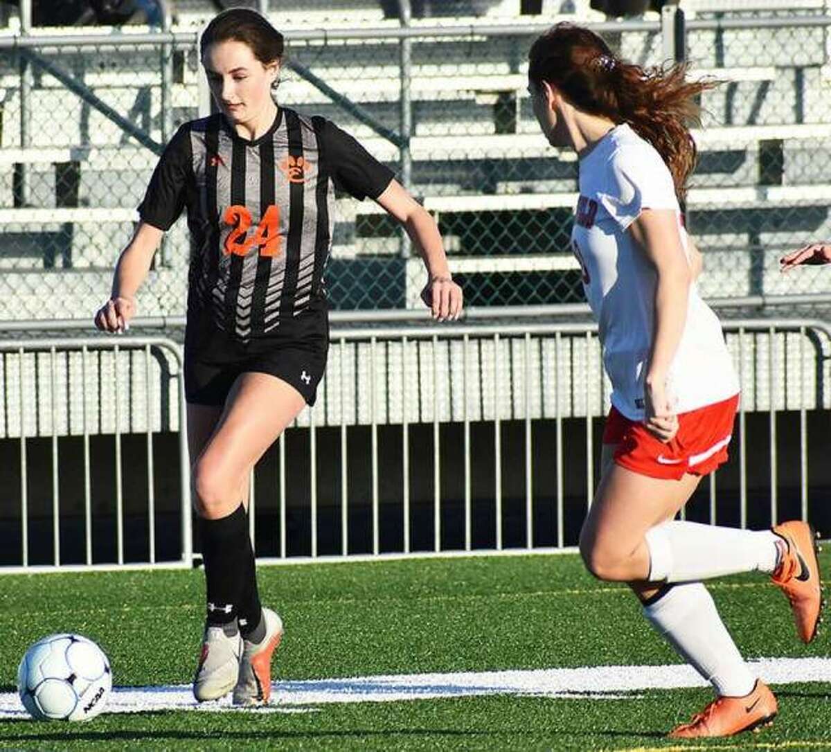 Edwardsville midfielder Rileigh Kuhns dribbles the ball down the field against a defender during a home game inside the District 7 Sports Complex.