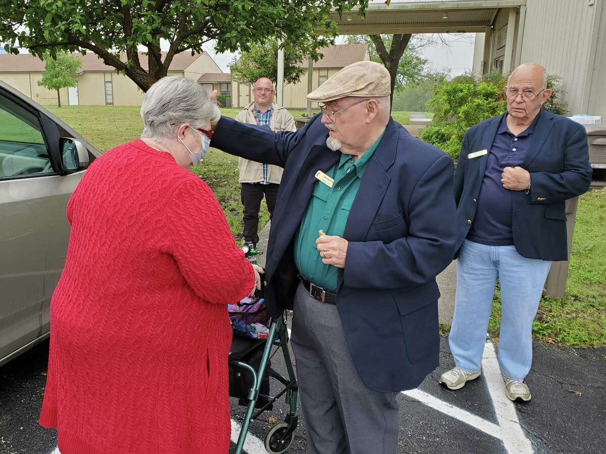 Alamo United Methodist Church pastor's assistant Tom Kinkead blesses and prays for church member Kathy Vedell Sunday during curbside service offered by the church on Foster Road near Kirby.