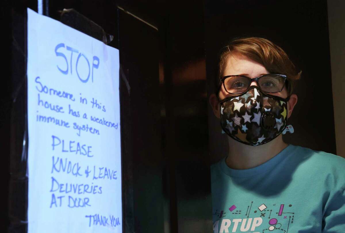 Jennifer Walker, who has a compromised immune system, wears a mask in an effort to ward off any illnesses, including the novel coronavirus. As the virus has spread in San Antonio, Walker placed a sign on her front door to warn delivery people of her condition.