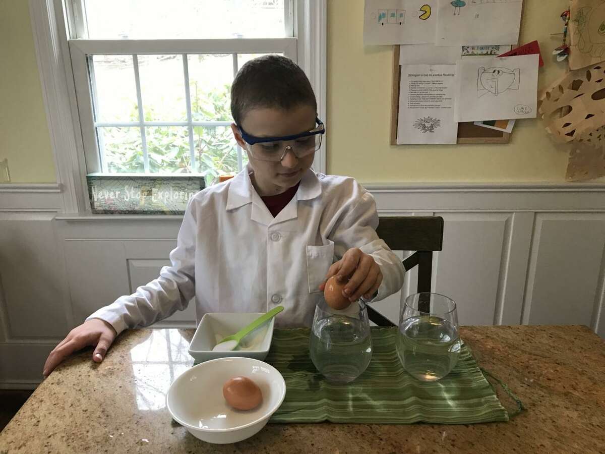 Luke Thornton, a third grader at Cider Mill School, conducts an egg experiment at home.