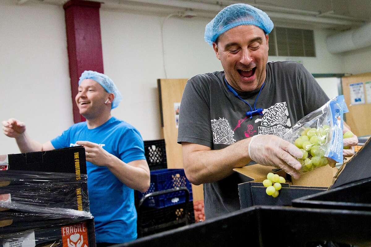 Grocery Services Supervisor Daniel Cohen (right) gets excited at the sight of grapes as he and Operations Director Michael McCormick (left) sort through fruit boxes donated by The Fruit Guys while in the volunteer space at Project Open Hand San Francisco, Calif. Wednesday, March 25, 2020. The Fruit Guys have found themselves with way too much fruit because their customers, mostly offices, who order their $50 fruit baskets have stopped ordering due to the shelter-in-place order issued amid the outbreak of the Coronavirus.