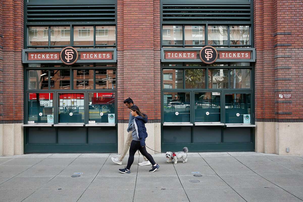 Pedestrians walk past the ticket windows at the box office at Oracle Park on Tuesday, March 17, 2020 in San Francisco, Calif.