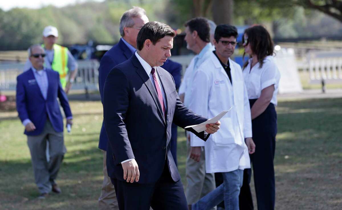 FILE- In this March 23, 20202 file photo, Florida Gov. Ron DeSantis, center front, arrives at a mobile testing site for a press conference Monday, March 23, 2020, in The Villages, Fla. The Villages, a retirement community, is one of the largest concentration of seniors in the U.S. Republican Gov. Ron DeSantis has been walking a tightrope for weeks during the coronavirus crisis, trying to protect both Floridians vulnerable to the virus and the cratering economy in a state of 21 million people. (AP Photo/John Raoux, File)