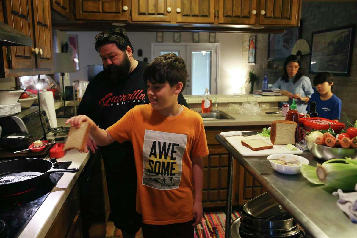 Jack Canter, 10, places toast in a buttered cast-iron pan as he makes a tuna melt. His father, chef James Canter, together with his mother and two brothers, are holed up at their home during the coronavirus crisis.