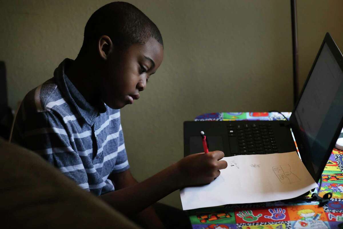 Christopher Leach, 9, a Larkspur Elementary School student, works online finishing his daily assignments. Nicole Hall Leach, 36, is taking A&M San Antonio courses online and her sons Marquette Leach Jr., 11, and Christopher are working on lessons from their schools as they shelter in place in their apartment.