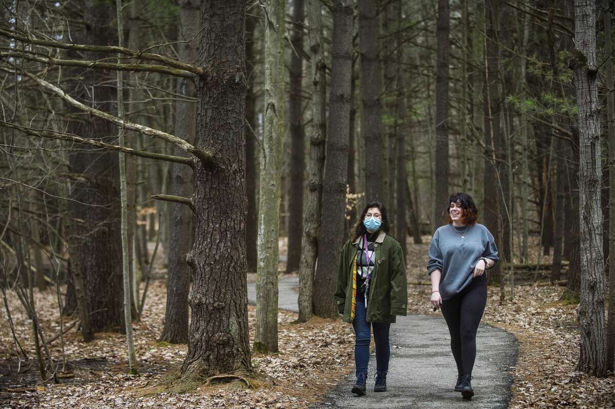 Taylor Propp, left, and Kai Klingbeil, right, both 21, stroll along a trail Thursday, March 26, 2020 at Chippewa Nature Center. Although the visitor center is closed, all trails at the nature center remain free and open to the public. (Katy Kildee/kkildee@mdn.net)