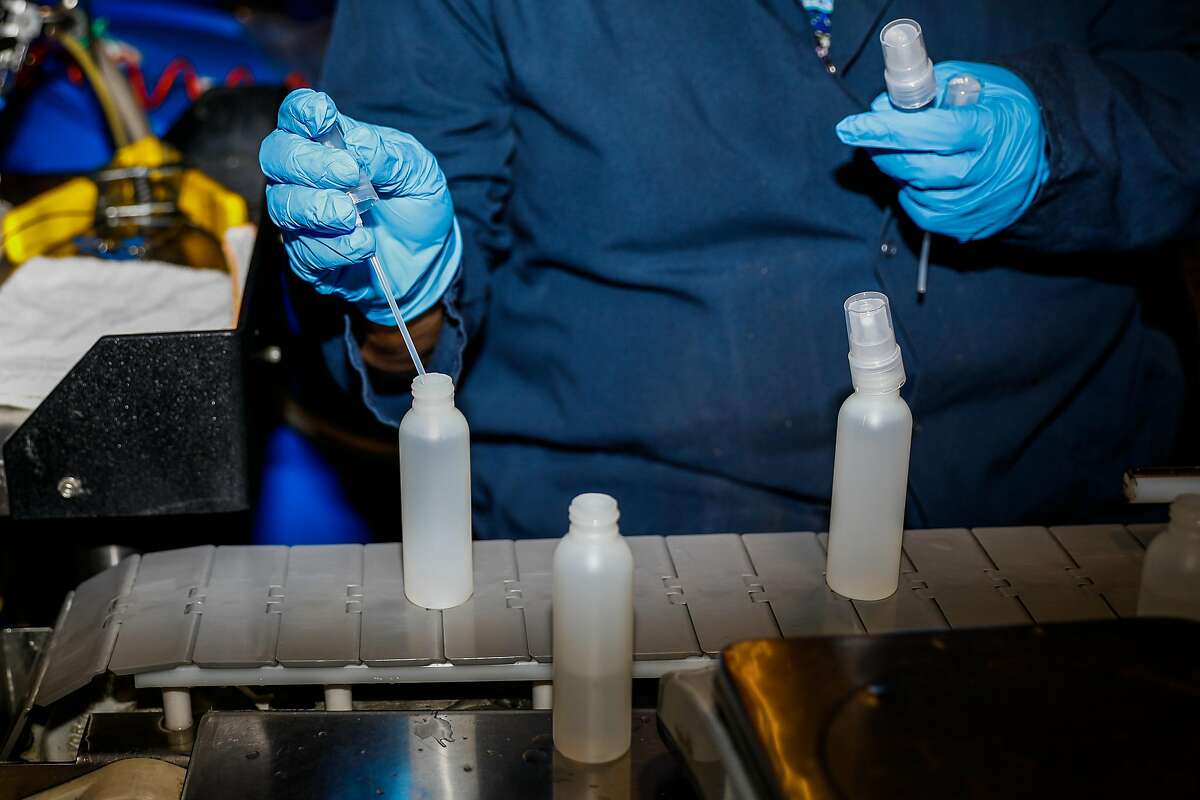 An employee puts a cap on the hand sanitizer as she work at the EO factory on Monday, March 23, 2020 in San Rafael, California. They have seen the demand for their product grow by over 1000% in the last month.