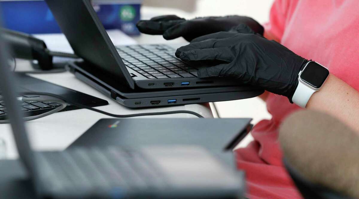 A woman works on a Chromebook laptop as New Caney ISD personnel issued laptops to students as the district works to implement remote learning at Keefer Crossing Middle School in New Caney. As legislation that would provide state funding for virtual school failed to pass the state Legislature this year, districts that had been preparing for an online option are shifting course.