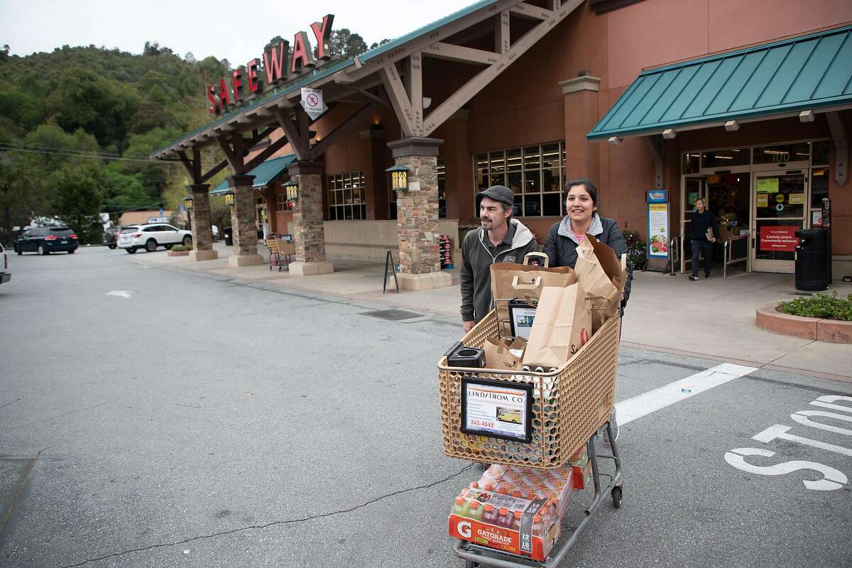 Daniel and Liliana Robertson, of Palo Alto, head to their vehicle after shopping at the Crystal Springs Village Safeway Monday, March 23, 2020, in San Mateo, Calif. Their Palo Alto Safeway didn’t have everything they were looking for so they came to the San Mateo store.