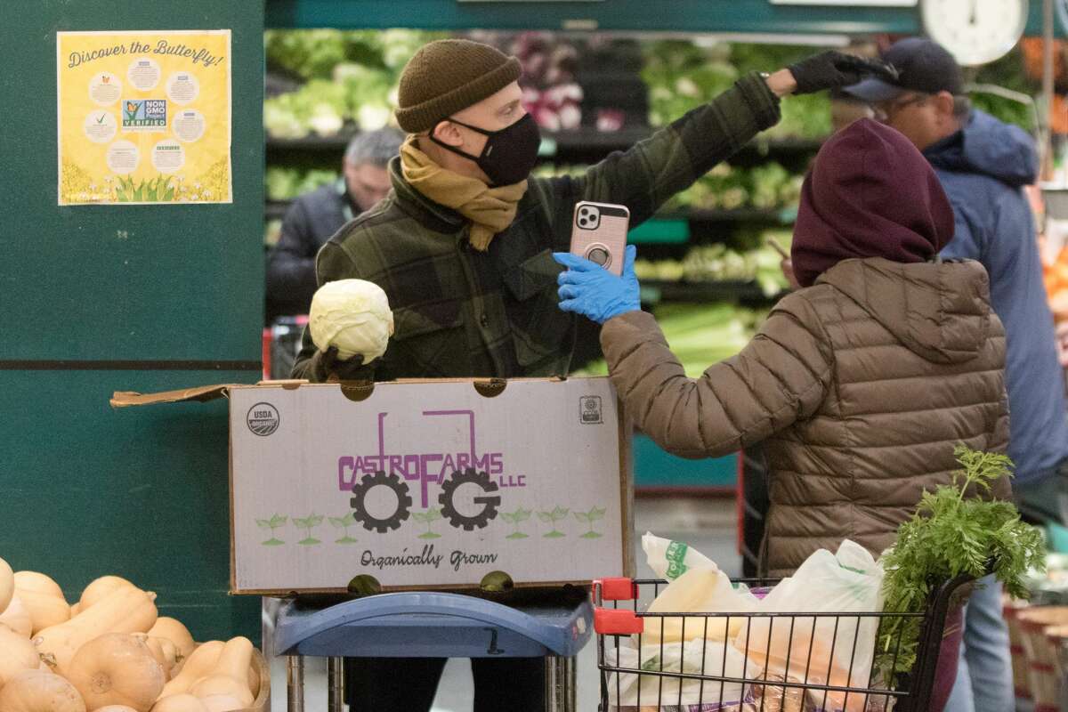 Co-Op Rainbow Grocery employee Maurice Roettele helps an InstaCart shopper find an item. The store has put in limits on the amount of customers inside grocery store to promote social distancing and help prevent the spread of Covid-19 coronavirus in San Francisco, Calif. on March 26, 2020.
