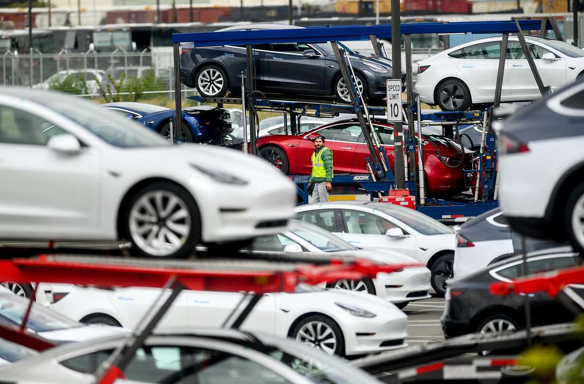 A worker loads Tesla vehicles onto trucks at the company's Fremont, Calif., factory on Wednesday, March 18, 2020. Activity continues at the facility despite Alameda County shelter-in-place orders implemented to limit spread of the coronavirus.
