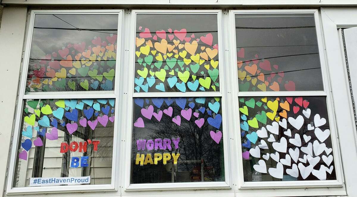 Stuck home all day from school, East Haven kids Bailey Montgomery, 10, left, and her cousin Elizabeth Melendez, 12, spent four hours cutting out dozens of multi-colored hearts and taping them all to the inside of the windows of Bailey's front porch -- like a rainbow -- accompanied by the twin messages, "Don't Worry, Be Happy" and "#EastHavenStrong."