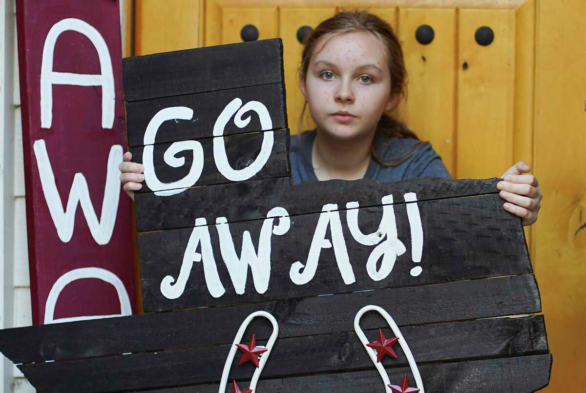 Issy Powell, 12, holds a sign she made outside her Kingwood home.