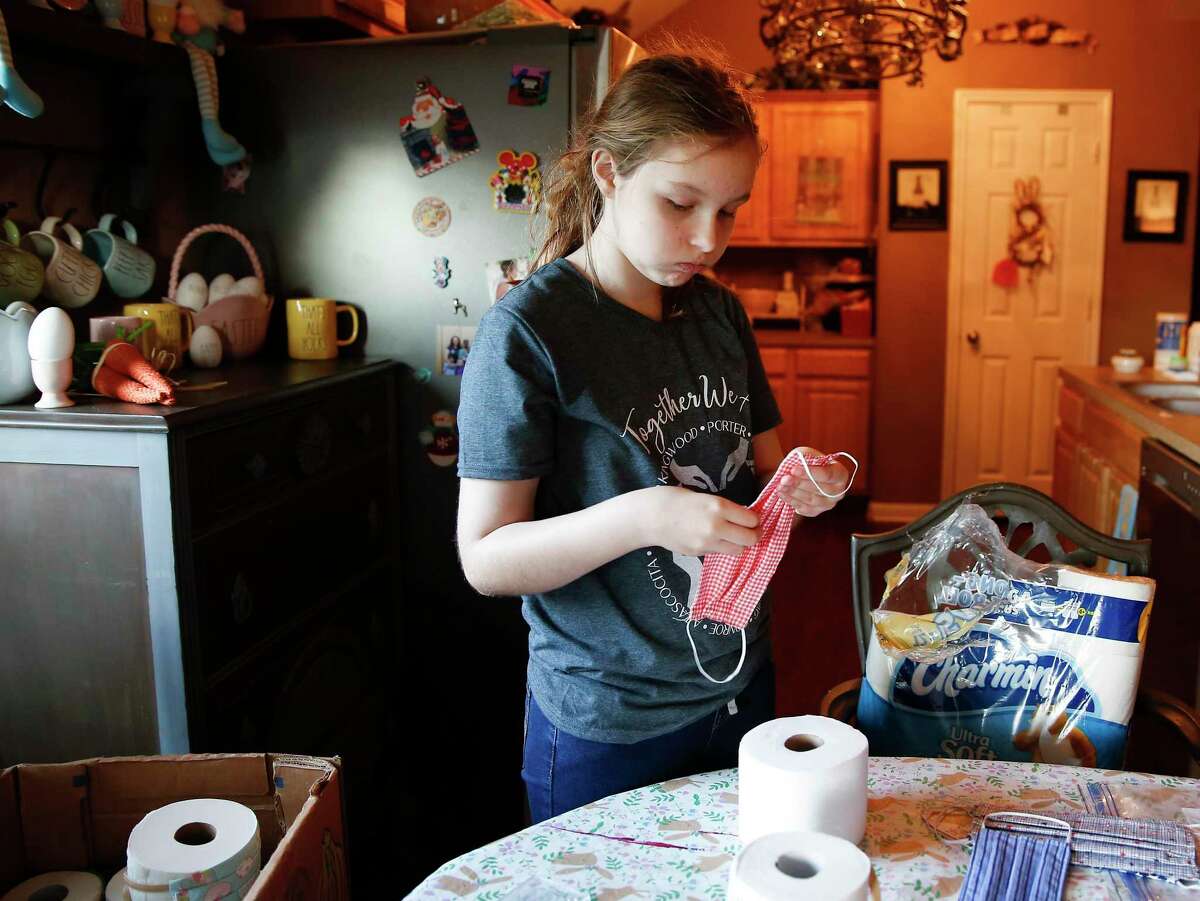 Issy Powell, 12, puts homemade face masks on rolls of toilet paper to donate.