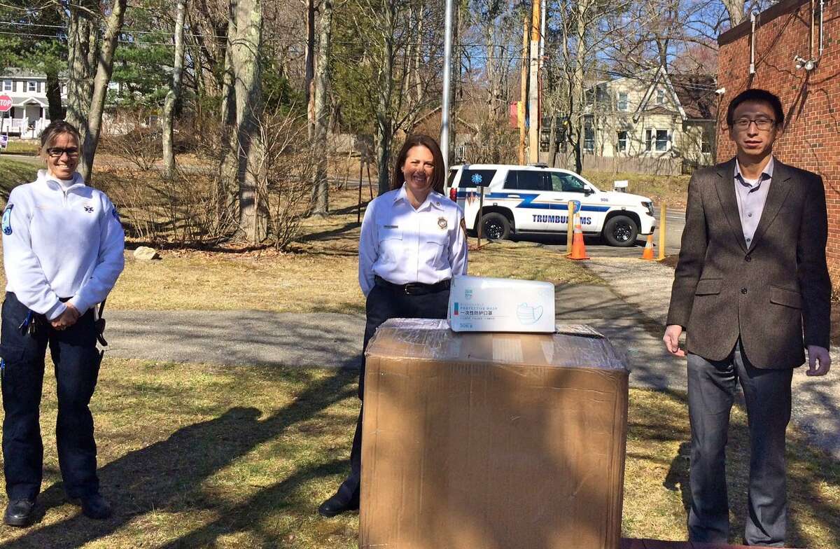 EMS Director Leigh Goodman, left, and Fire Marshal Megan Murphy accept a donation of 1,700 protective masks from Jing “Jack” Jiang of Trumbull, who made the donation on behalf of the town’s Chinese-American community.