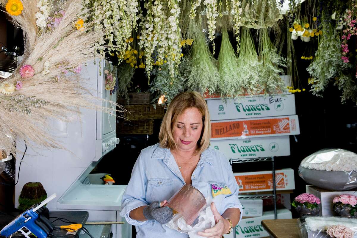 Florist Jennifer Carruthers works on flower arrangements in the garage of her home in San Francisco, Calif. Wednesday, March 25, 2020. Carruthers has been creating dried flower arrangements for various local and wholesale companies since the 1980s. She usually works out of San Francisco's Flower Mart, but it has closed due to the outbreak the of Coronavirus. She now operates out of her garage, but is unsure of the future since she's unable to sell her arrangements at the Flower Mart or local farmer's markets.
