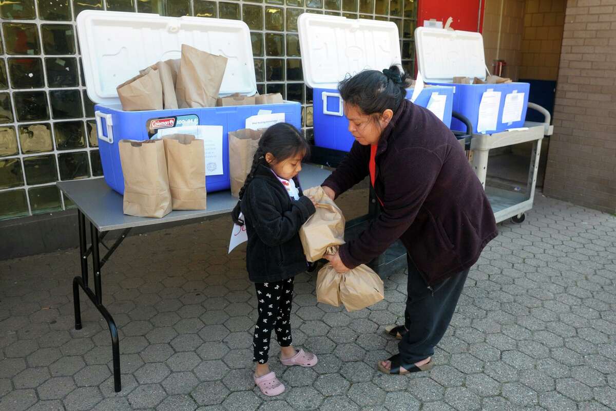 Maria Mecatl picks up grab-and-go meals with her niece, Isabella Valez, at Curiale School in Bridgeport, Conn. March 27, 2020. Bridgeport schools have expanded the program from breakfast and lunch to also include items for dinner meals.