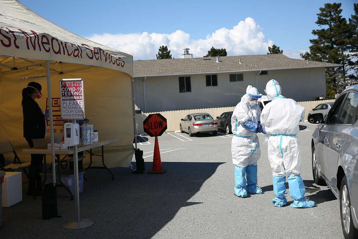 Sandar Htun, M.D. (right) and Whitney Lao (second from right), medical assistant, work as they conduct COVID-19 tests at a drive-through testing site in the parking lot at the North East Medical Services Daly City Clinic on Thursday, March 26, 2020 in Daly City, Calif.