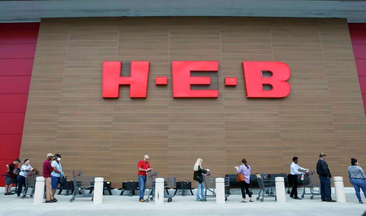 H-E-B employee Chermane Goldson sanitizes customers carts as they wait outside for the store to open, Wednesday, March 25, 2020, at the H-E-B in Bellaire.