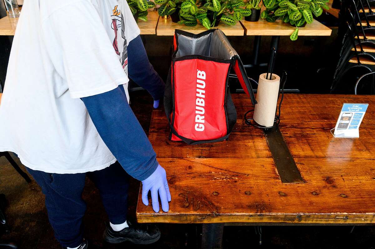 A Grubhub driver waits for an order. A new California law requires delivery companies to have agreements with restaurants before listing them on their apps.